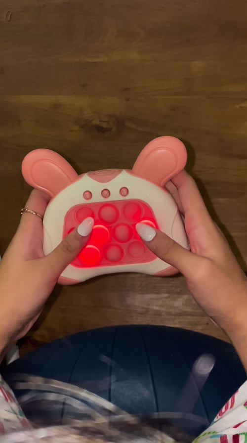 Hands holding the pink bunny push game with lit red bubbles