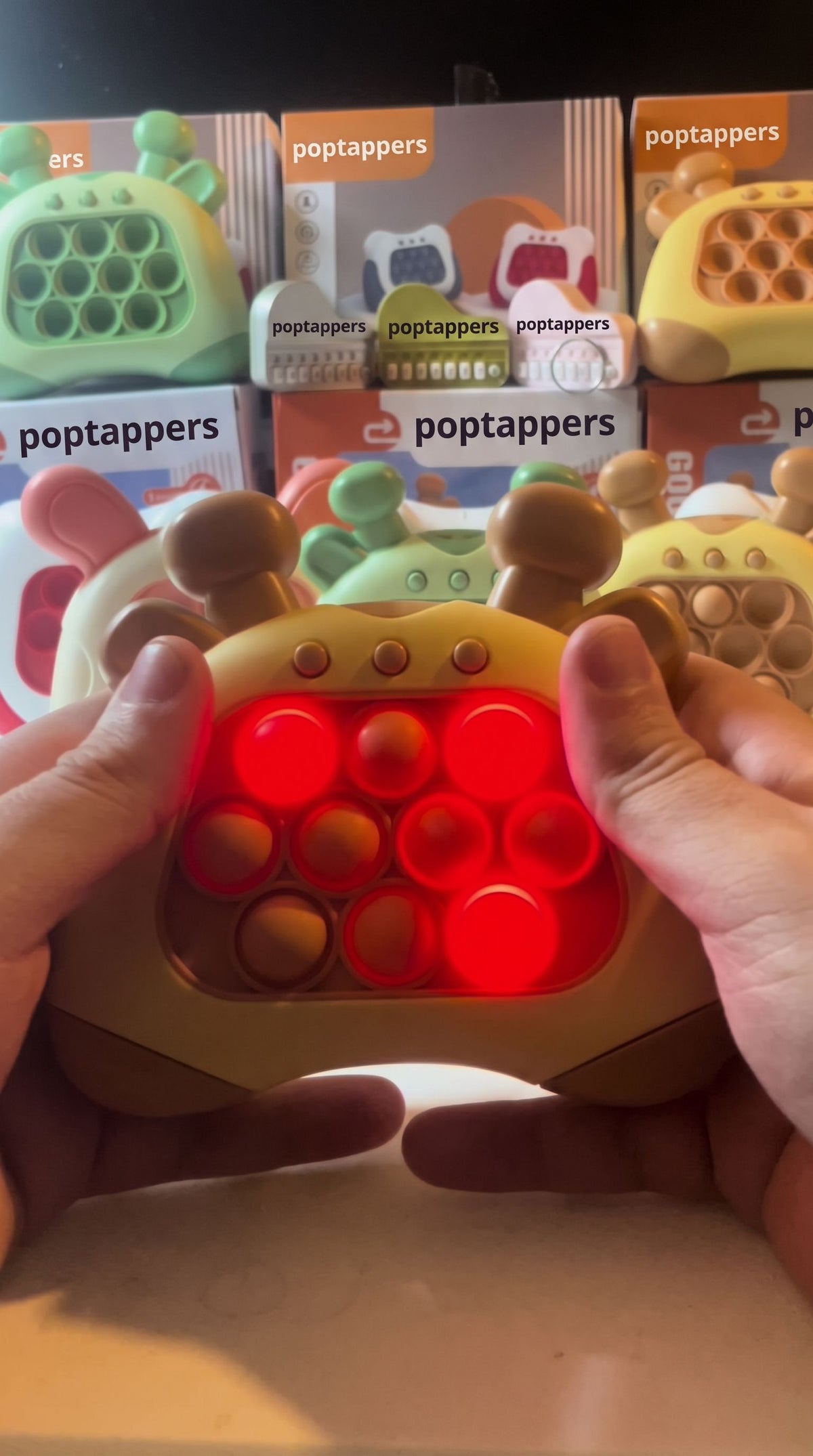 Hands holding the brown giraffe push game in front of Poptappers boxes