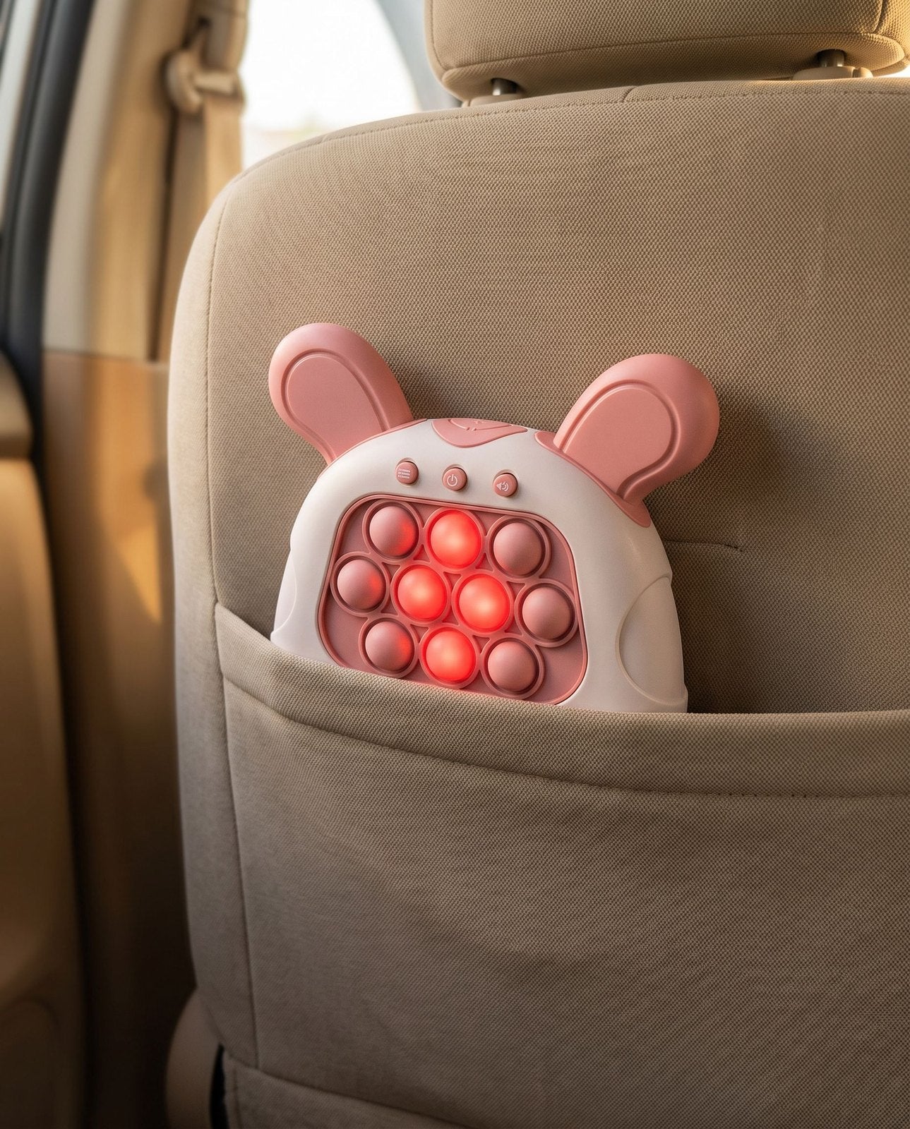 The pink bunny push game tucked into the seat pocket of a car