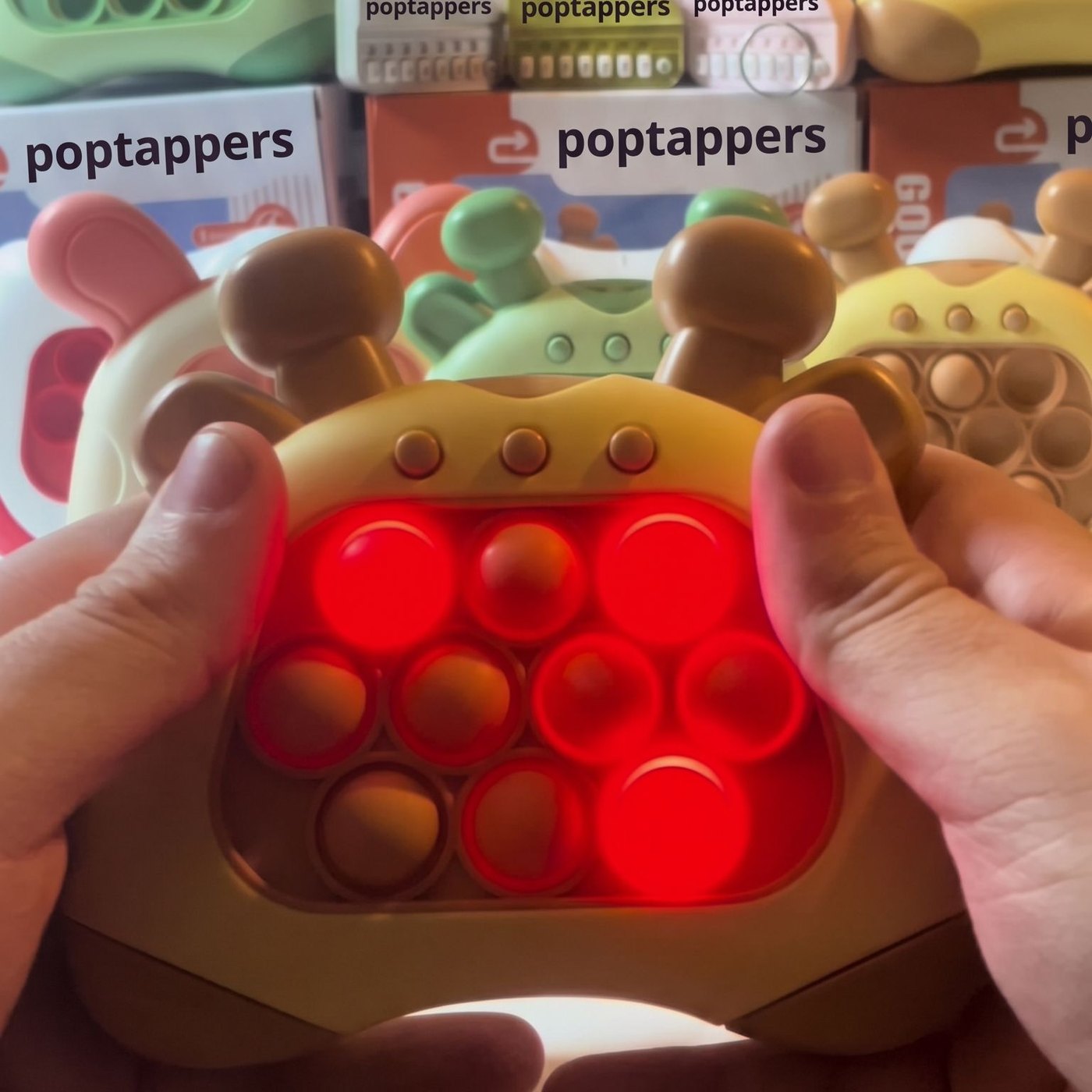 Hands holding the brown giraffe push game in front of Poptappers boxes